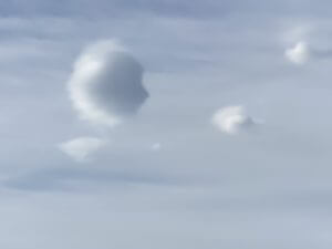 A single soft white cloud drifting in a pale blue sky.