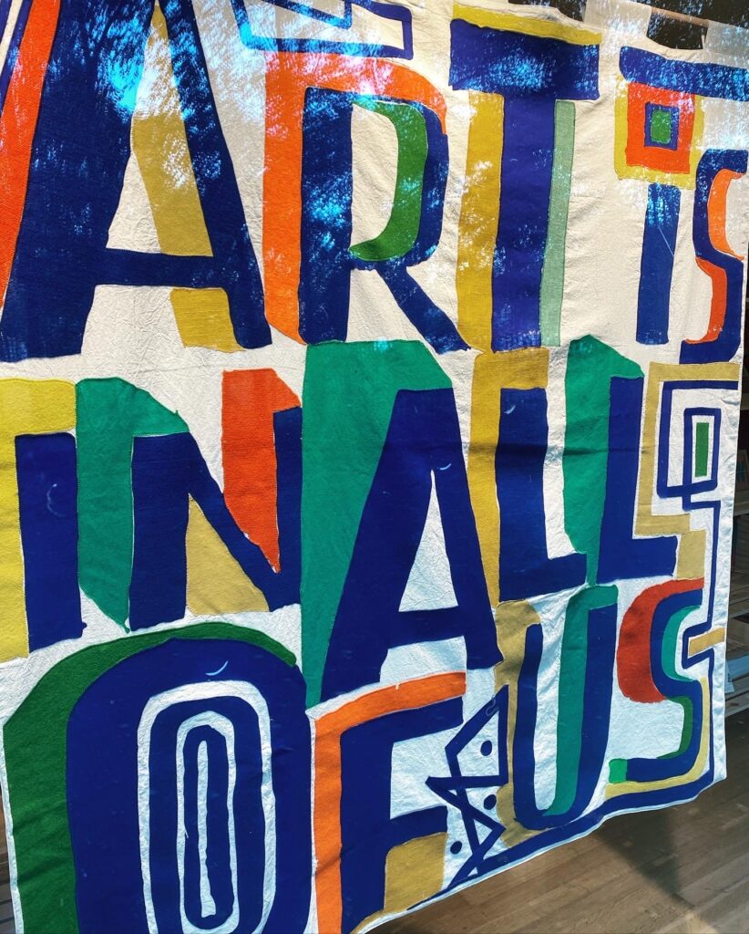 A brightly painted mural spelling out the words art is all of us.