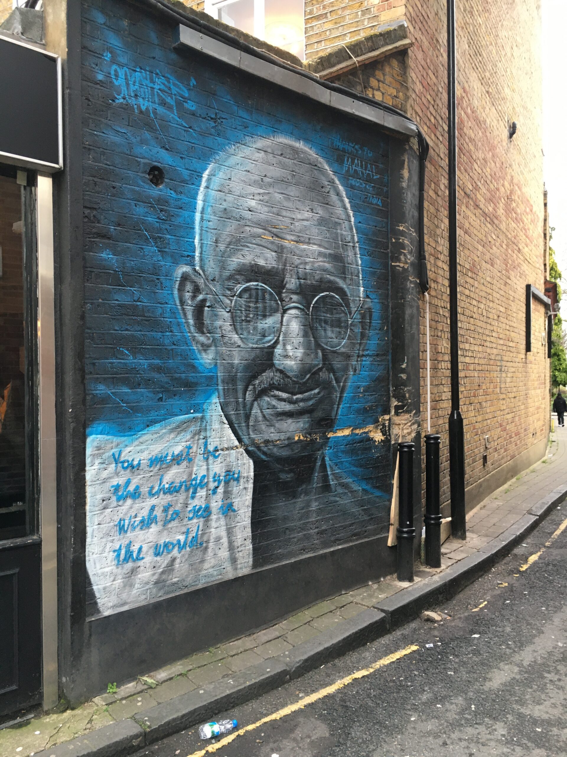 A street mural of Gandhi painted on a brick wall in an Islington back street, London