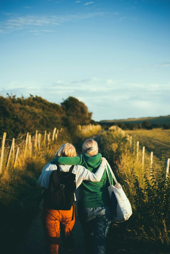 Two people close together in a field of tall grass in late afternoon light.
