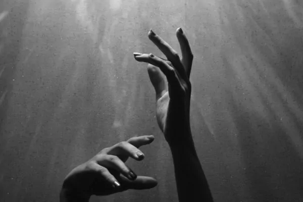 Spiritual Bypassing: When Practice Becomes a Place to Hide Alex Golding Therapy A hand reaching upward through darkness towards the light.