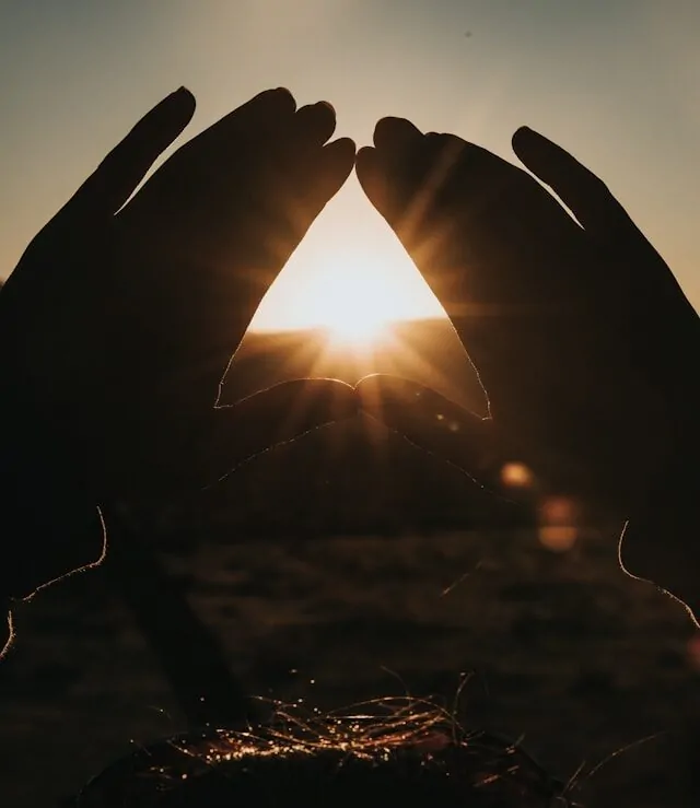 Love, Loss & the Art of Intimacy Alex Golding Therapy Two hands raised to frame the low sun between them.