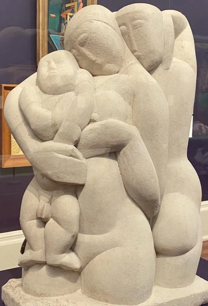 A pale stone sculpture of two figures curved around one another.