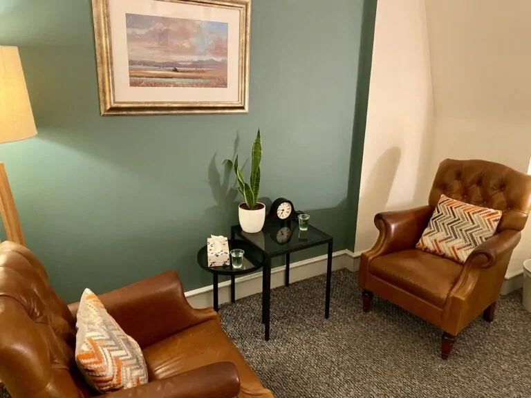 Home Alex Golding Therapy The Farringdon consulting room, with two leather armchairs, a side table and a lamp.