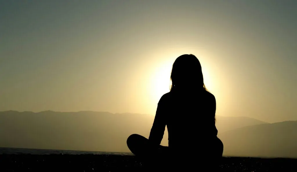 All Spirit, No Ground. All Ground, No Meaning. Alex Golding Therapy A person sitting cross-legged on a hilltop with the ground falling away, one of the two dimensions of growth without the other.