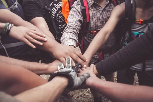Toxic Friendships: Signs, Why They Hurt & How to Heal Alex Golding Therapy A group of people reaching in to place their hands together in a circle.
