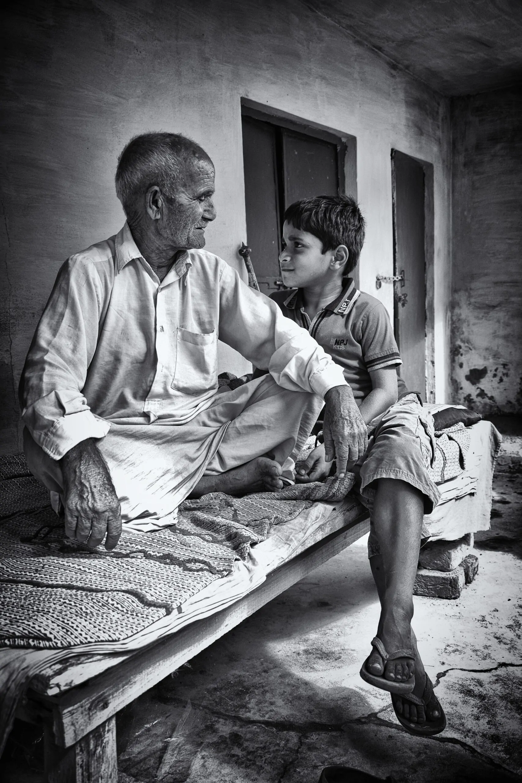 The World Beyond Your Skin Alex Golding Therapy An older man and a boy sitting together outside a house, turned towards each other in conversation